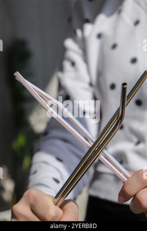 Woman holding Reusable Metal and plastic drinking Straws. Female Hand on reusable collapsible drinking straw. Eco lifestyle and zero waste concept. Pl Stock Photo