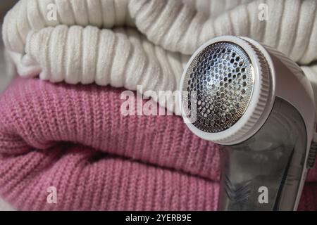Anti-pilling razor. Device for shaving clothes. Anti-Plush fabric Shaver. Electric portable sweater pill defuzzer Lint remover from pink acrylic or wo Stock Photo