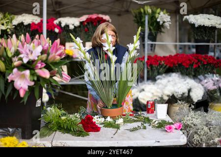 Madrid, Madrid, Spain. 1st Nov, 2024. A woman prepares a floral arrangement for sale in front of the Almudena cemetery, during the celebration of All Saints' Day.The Almudena cemetery is named after the patron saint of Madrid and is the largest cemetery in Western Europe. (Credit Image: © Luis Soto/ZUMA Press Wire) EDITORIAL USAGE ONLY! Not for Commercial USAGE! Stock Photo