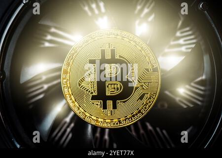 Bitcoin on cooling computer fan background. Golden bitcoin coin on spinning blades of ventilator Stock Photo