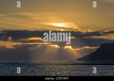 Colourful cloudscape lit by rising sun over stormy waves of Pacific ...