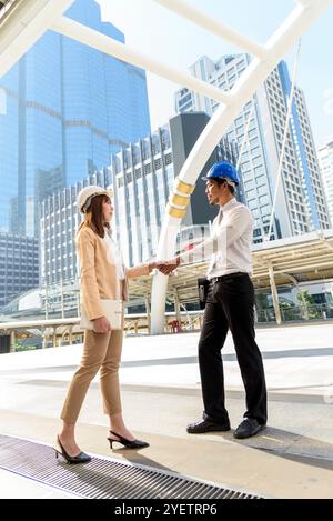 Civil Construction engineer teams shaking hands together wear work helmets worker on construction site. Foreman industry project working engineer team Stock Photo