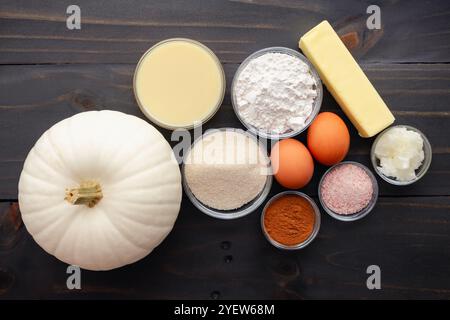White Pumpkin Pie Ingredients on a Wooden Table: White pie pumpkin with flour, sugar, pumpkin spice, and other pumpkin pie ingredients Stock Photo