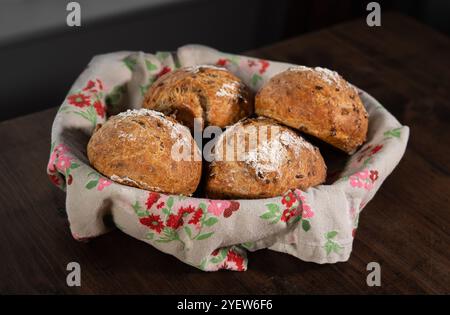 Classic farm country bread buns in a cute basket next to a mug, butter, salt, pepper. These homemade rustic rolls balls are made of organic wholemeal Stock Photo