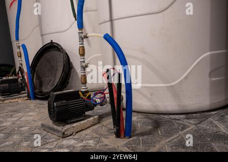 Close-up of industrial water pumps connected with blue and red hoses in a facility. Essential equipment for liquid management and flow control. Stock Photo