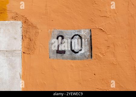 Number twenty on rough panel on plaster wall Stock Photo