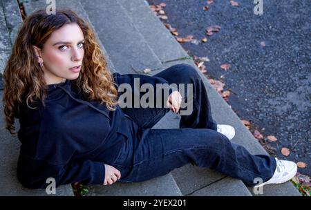 Lovely female model Ava Nicholson relaxes on the stairs of the Dundee neoclassical Camperdown House, sheltered from the autumn sunshine, Scotland Stock Photo