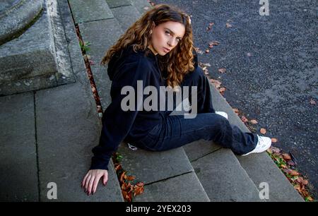 Lovely female model Ava Nicholson relaxes on the stairs of the Dundee neoclassical Camperdown House, sheltered from the autumn sunshine, Scotland Stock Photo