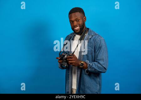 smiling black man with camera isolated on blue background Stock Photo