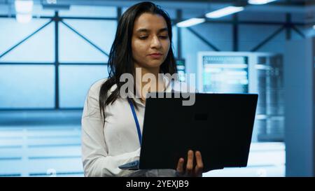 System administrator in data center monitoring security threats, implementing cybersecurity measures. Woman ensuring compliance with regulations to protect data center gear, camera A Stock Photo