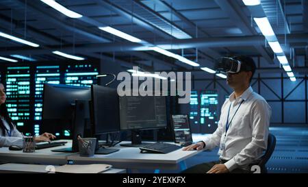 Engineer wearing VR headset in data center installing software on computer, troubleshooting issues. IT expert in server hub using virtual reality tech, establishing performance benchmarks, camera B Stock Photo