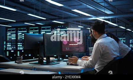 Computer scientists in server room protect hardware from hacker attack stealing sensitive information. Data center cybersecurity division teamworking colleagues fighting security breach, camera B Stock Photo