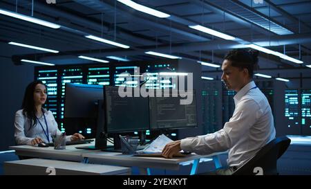 System administrator in data center maintaining accurate paperwork of hardware, generating reports. IT expert in high tech server farm doing workplace disaster recovery planning, camera B Stock Photo