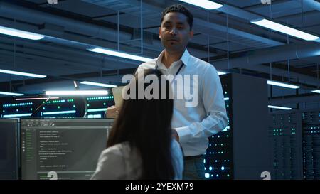 Team of researchers in data center monitoring security threats using PC, implementing cybersecurity measures. Teamworking colleagues ensuring compliance with regulations, camera A Stock Photo