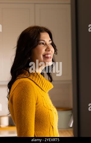 Smiling woman in cozy sweater enjoying warm moments at home Stock Photo