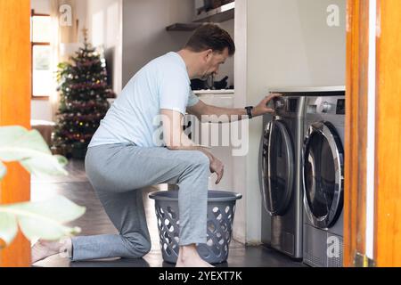 senior man doing laundry at home with Christmas tree in background Stock Photo