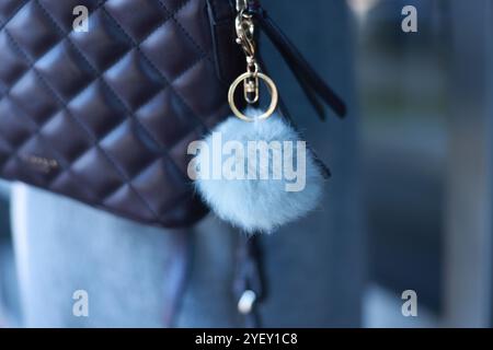 Woman with faux fur keychain on her backpack outdoors, closeup. Selective focus Stock Photo