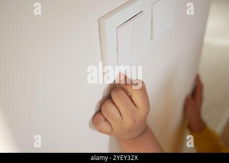 child finger turning on lighting switch with copyspace  Stock Photo