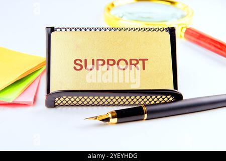 Business concept. The phrase, the text, the words SUPPORT are written on a gold business card on a light background. Stock Photo
