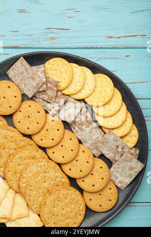 Different crackers on plate on blue wooden background. Top view Stock Photo