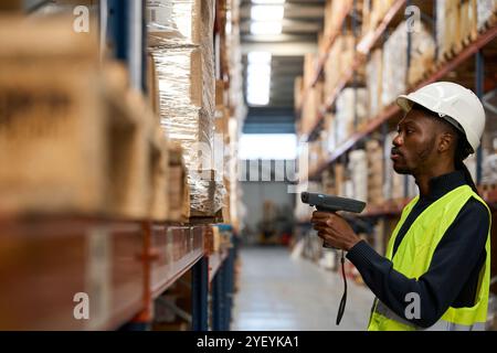 Logistics employee using handheld scanner on packages in warehouse Stock Photo