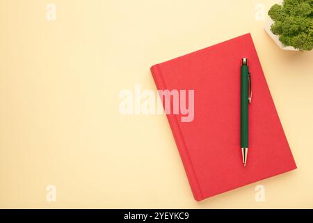 Red notebooks and pen on beige background, top view. Stock Photo
