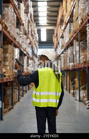 Logistics employee using handheld scanner on packages in warehouse Stock Photo