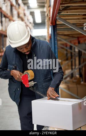 Warehouse worker sealing cardboard box with packing tape Stock Photo