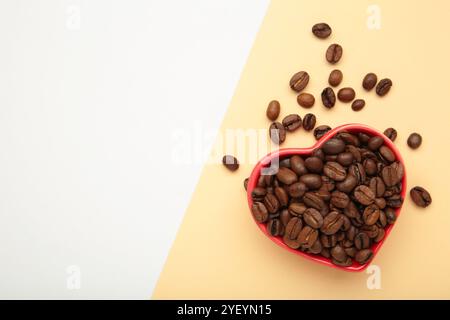 Coffee beans in the heart shaped bowl isolated on light background. Space for text Stock Photo