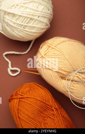 Different yarns, knitting needles on brown background. Top view Stock Photo