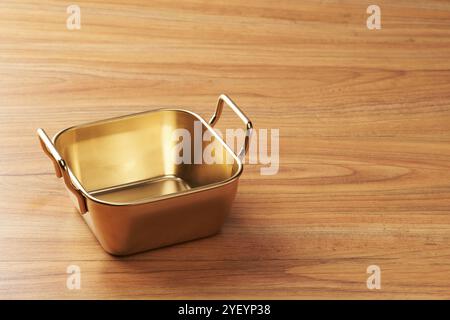 An empty aluminum container on a wooden table Stock Photo