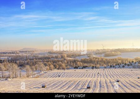 Winter landscape view at a valley with bales on a stubble field in the countryside, Sweden, Europe Stock Photo