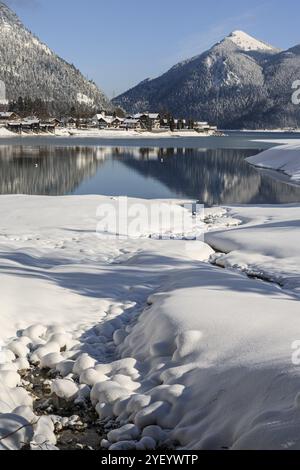 Mountains reflected in lake, village, houses, winter, snow, sunny, Walchensee, behind Jochberg, Bavaria, Germany, Europe Stock Photo