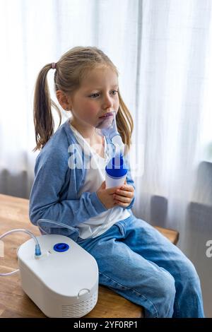 A 5-year-old girl at home uses a nebulizer, taking deep breaths to aid her respiratory health. High quality photo Stock Photo