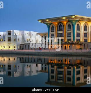 The front gate of Al Alam Palace in Muscat, Oman, reflects on water during the serene blue hour, showcasing royal elegance. Stock Photo