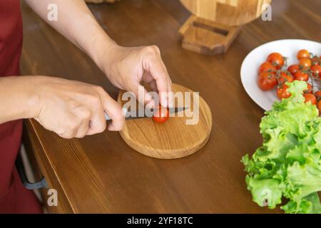 person cutting cherry tomatoes on cutting board Stock Photo
