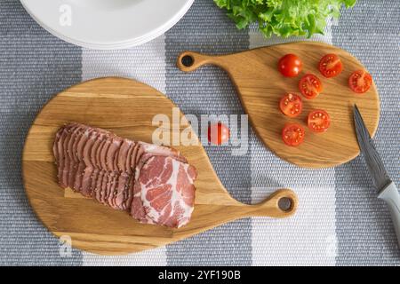 cherry tomatoes and sliced ham on a cutting boards on a table Stock Photo