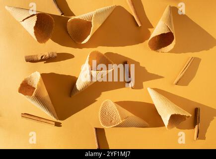 Ice cream cones and cinnamon sticks arranged on an orange background Stock Photo
