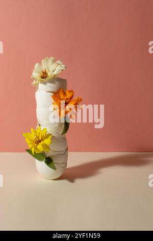 white eggshells with flowers arranged in a vertical row on a pink background. Still life Stock Photo