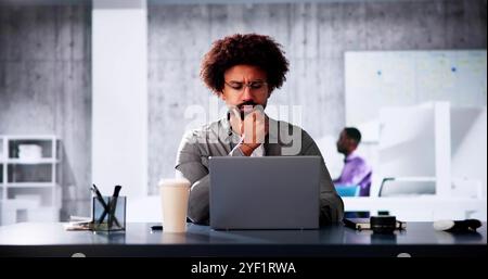 African American Businessman Working On His Laptop At His Desk In The Office, Planning Marketing Strategies For His Company. Stock Photo