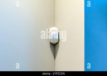 Alarm system presence detector on a wall with space for text with white background and blue right side Stock Photo