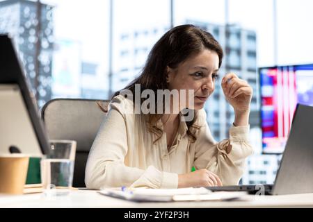 Empowered influential businesswoman evaluates company performance, using data reports and analytics to make informed decisions that optimize efficiency and productivity. Work ethic. Stock Photo