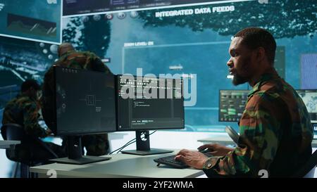 Military specialist in a high tech control center managing satellite radar surveillance, collecting intelligence on cctv systems. Interpreting real time data to ensure national defense. Camera B. Stock Photo