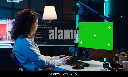 Freelancing admin using green screen computer monitors to filter malicious traffic from cybercriminals attempting to corrupt company data. IT expert in apartment working on mockup desktop PC, camera A Stock Photo