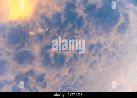 Altocumulus clouds on blue sky and sun at sunset. Background. Stock Photo