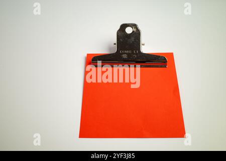 Black clipboard holding a bright red paper on a white surface Stock Photo