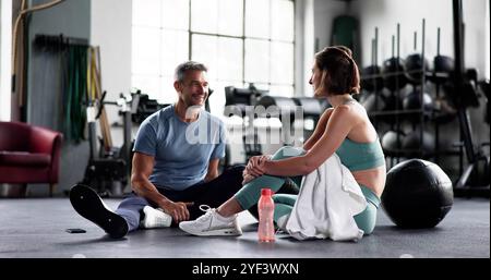 Smiling Couple Talking In Gym. Resting After Workout Together Stock Photo