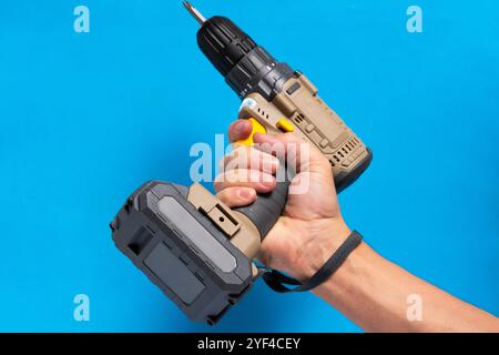 Man hand holds cordless screwdriver on blue background Stock Photo