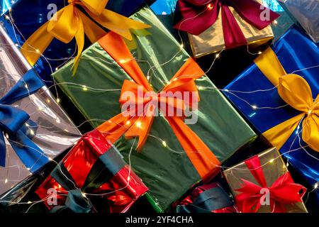 A vibrant arrangement of wrapped gift boxes with colorful ribbons and twinkling string lights, creating a festive and cheerful display. Stock Photo