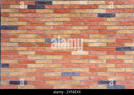 Brick wall with bricks in various colors, primarily in shades of red, orange, and beige, with some darker, almost black bricks. Stock Photo